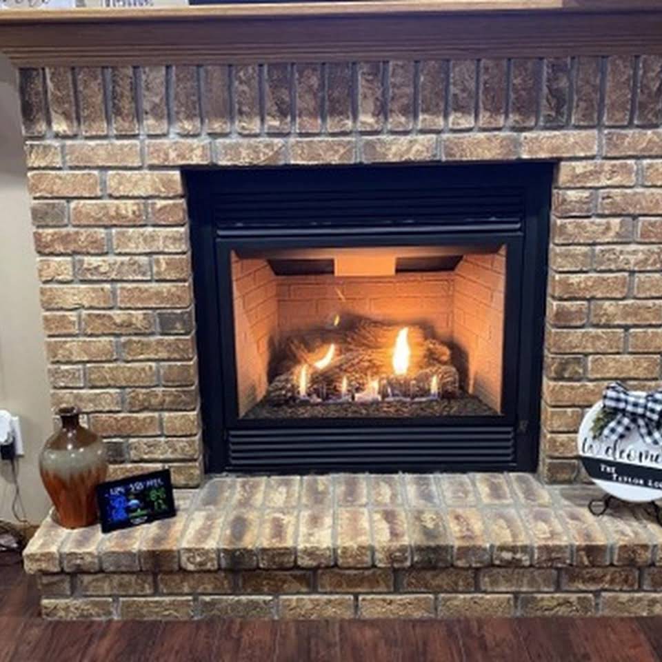 A cozy brick fireplace with a warm fire burning inside.