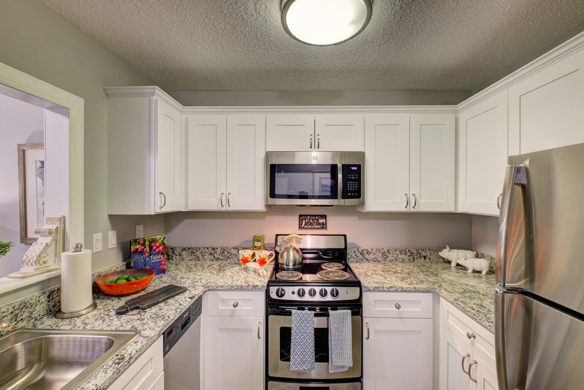 Modern kitchen with white cabinets and granite countertops featuring stainless steel appliances.