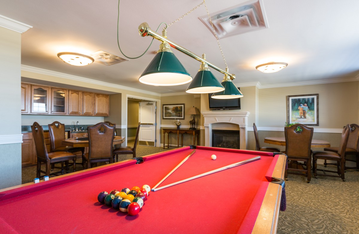 A cozy game room featuring a red pool table and comfortable seating.