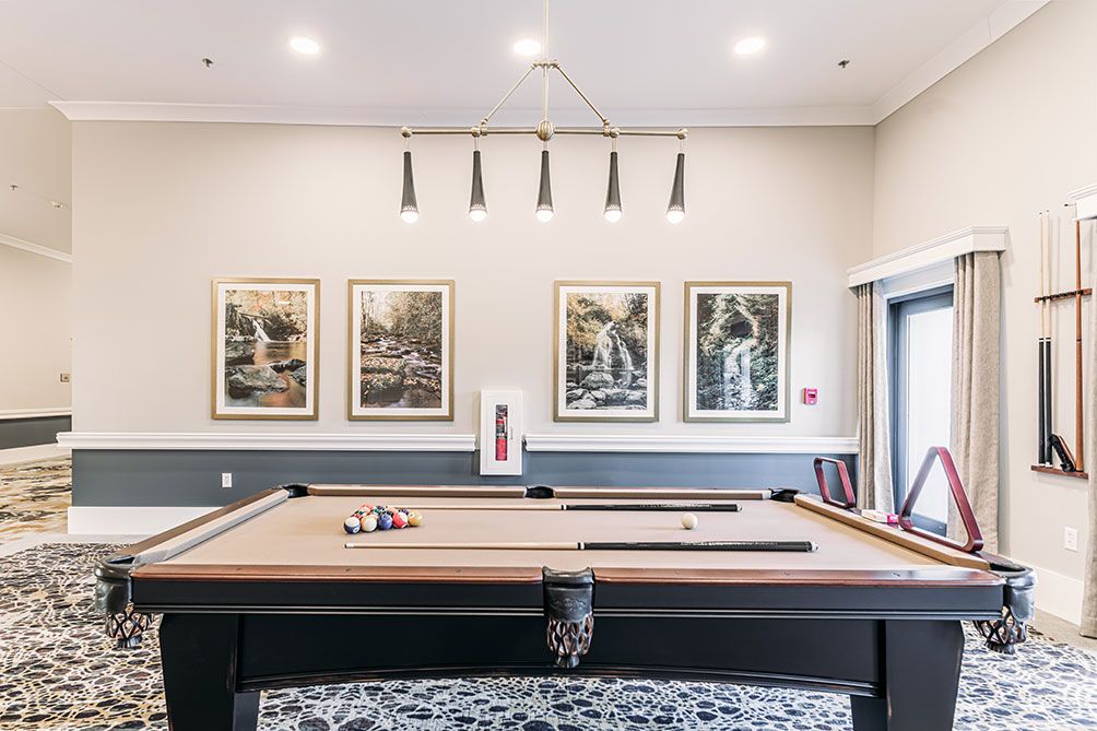A well-appointed billiard room featuring a pool table, framed artwork on the walls, and modern lighting.