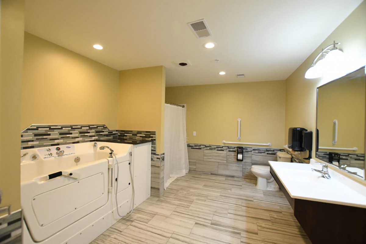 A spacious and modern bathroom with a bathtub, toilet, and sink, featuring stylish tile flooring and ample lighting.