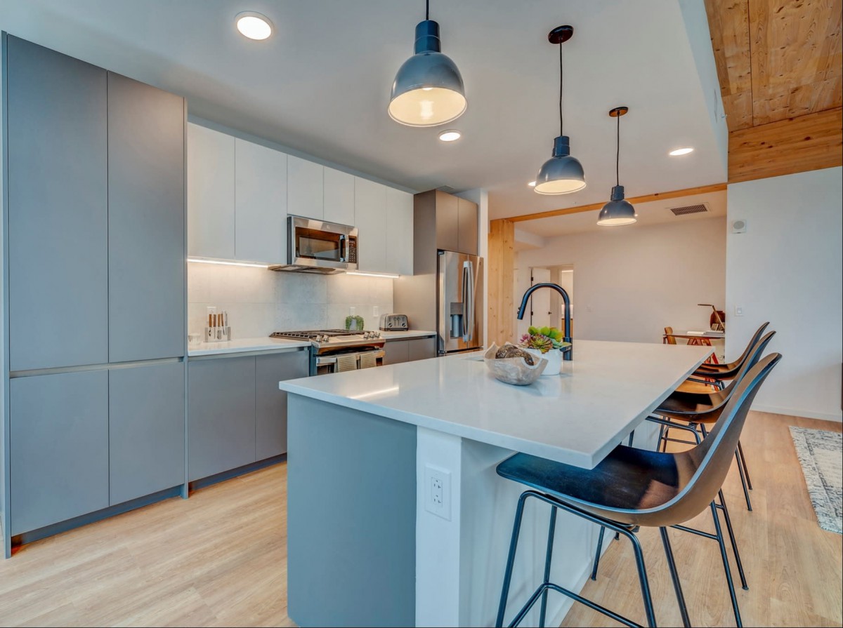 A modern kitchen featuring sleek cabinetry, a spacious island with bar stools, and contemporary pendant lighting.