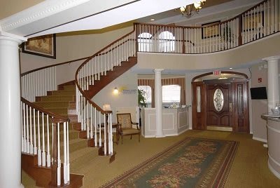An elegant interior lobby with a curved staircase and classic furnishings.