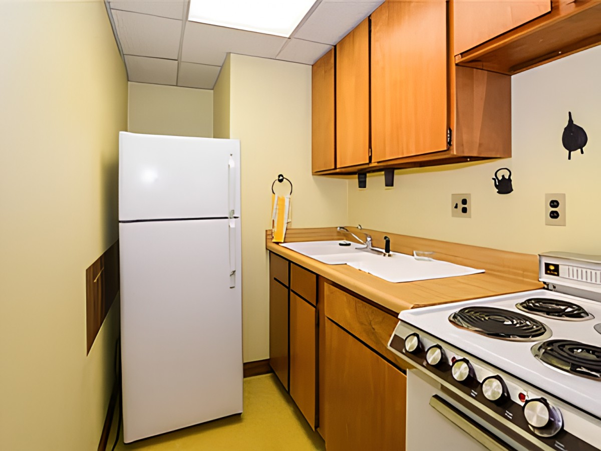 A compact kitchen with wooden cabinets, a fridge, and a stove.
