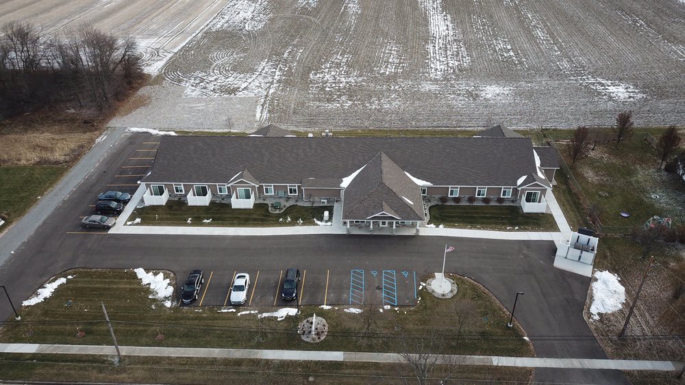 Aerial view of a building with a parking lot surrounded by snowy fields.