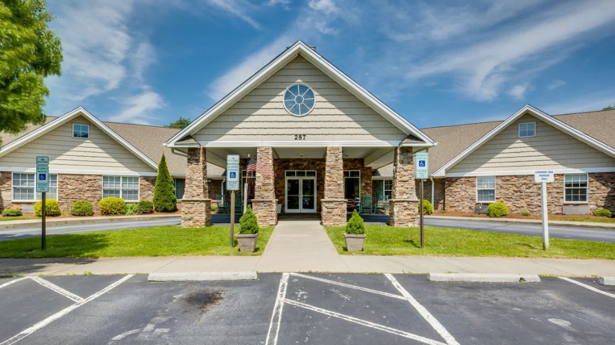 A commercial building entrance with stone columns and a well-maintained parking area.