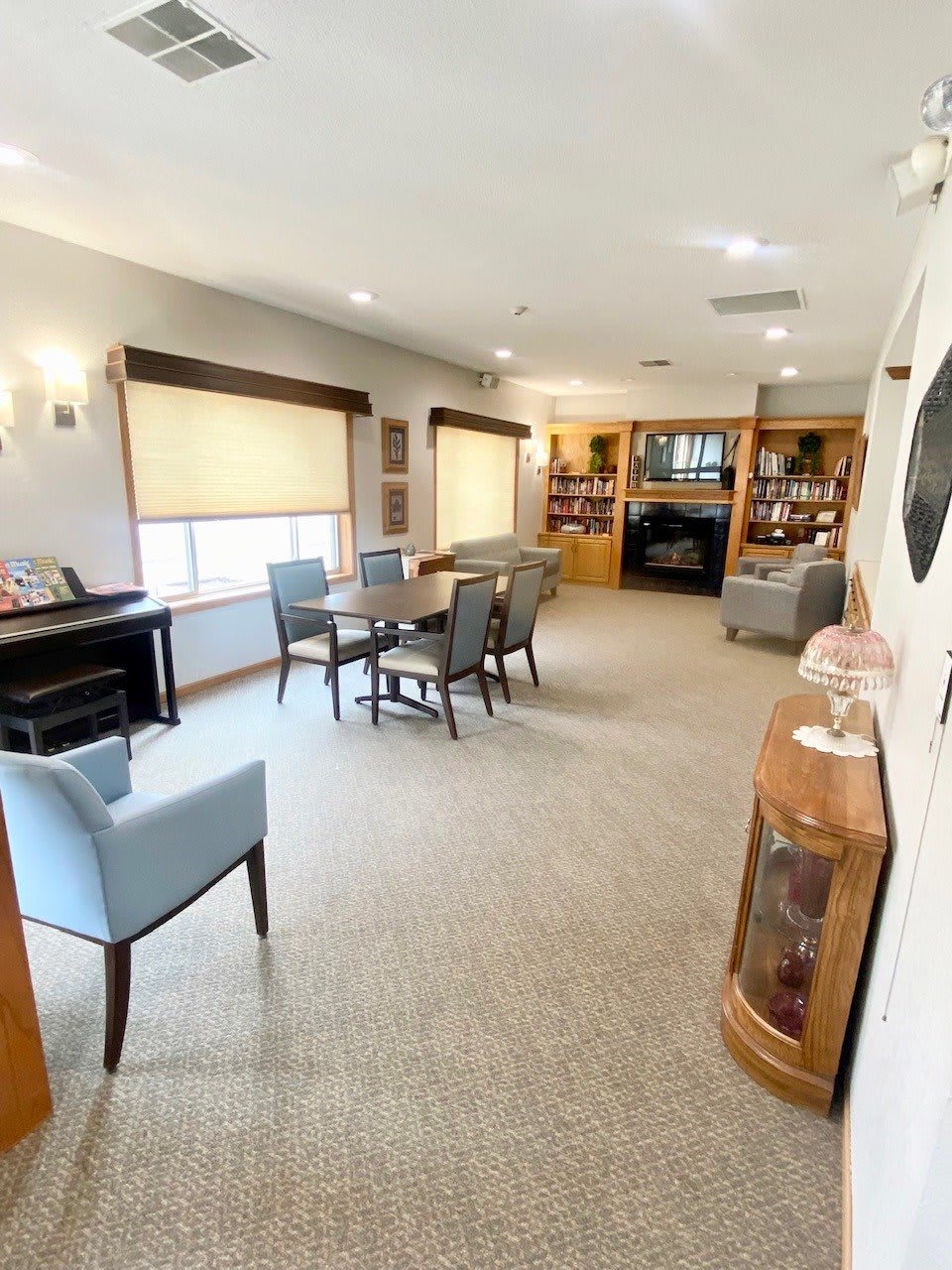 A spacious living room with elegant furniture, featuring a piano and bookshelves.
