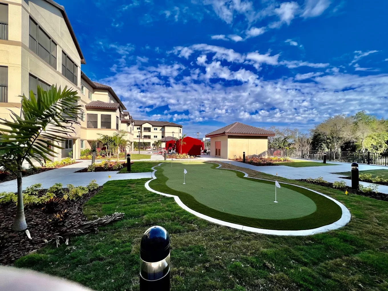 A scenic view of a resort with a well-maintained putting green under a vibrant sky.