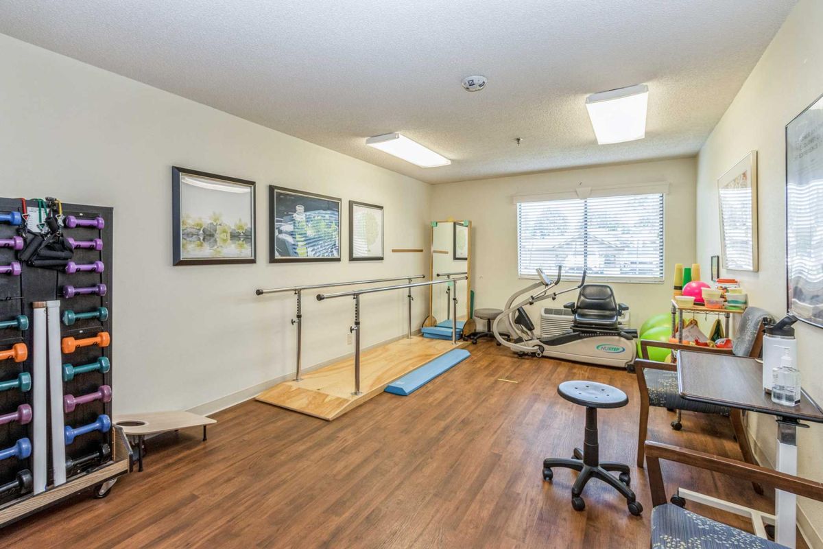 A rehabilitation room equipped with exercise equipment and parallel bars for physical therapy.