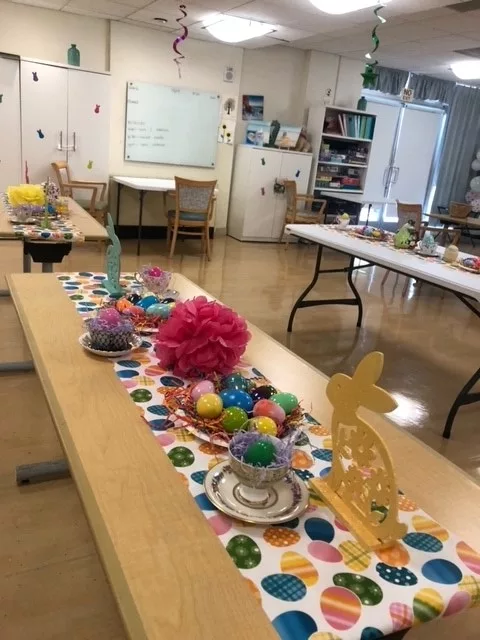 A classroom decorated for Easter with colorful crafts and ornaments on tables.
