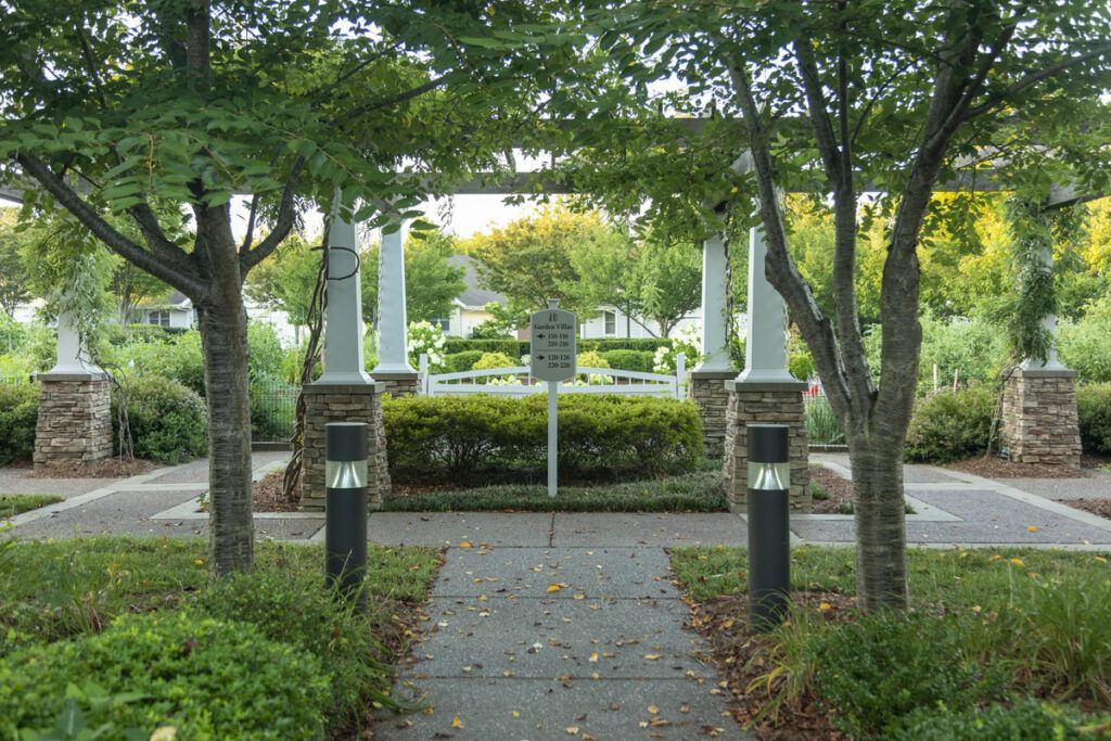 A serene garden pathway lined with trees and shrubbery, leading to a stone gazebo.