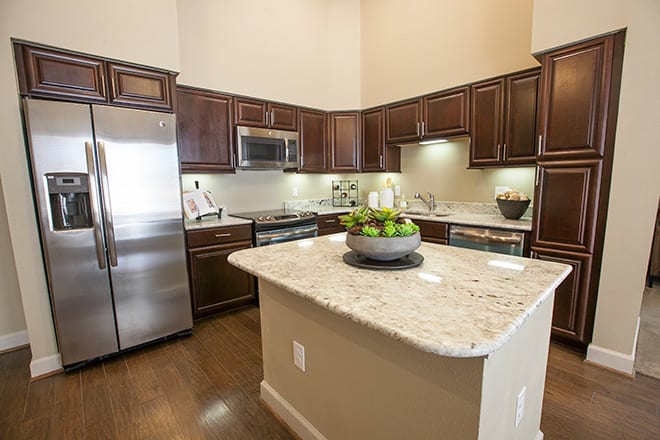 A modern kitchen featuring granite countertops, dark wood cabinets, and stainless steel appliances.