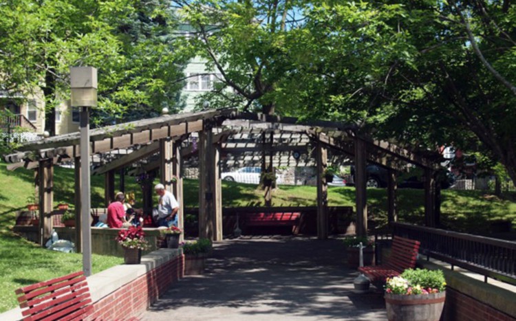 A scenic view of a park with a gazebo, benches, and people enjoying the outdoors.