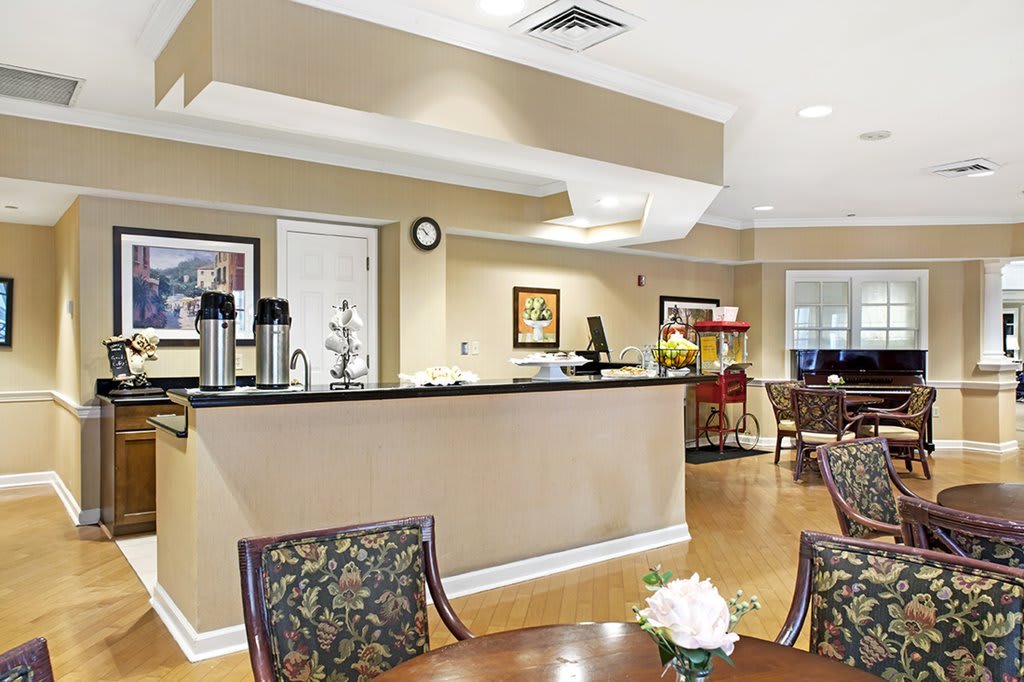 A modern lobby with a reception desk, coffee station, and seating area.