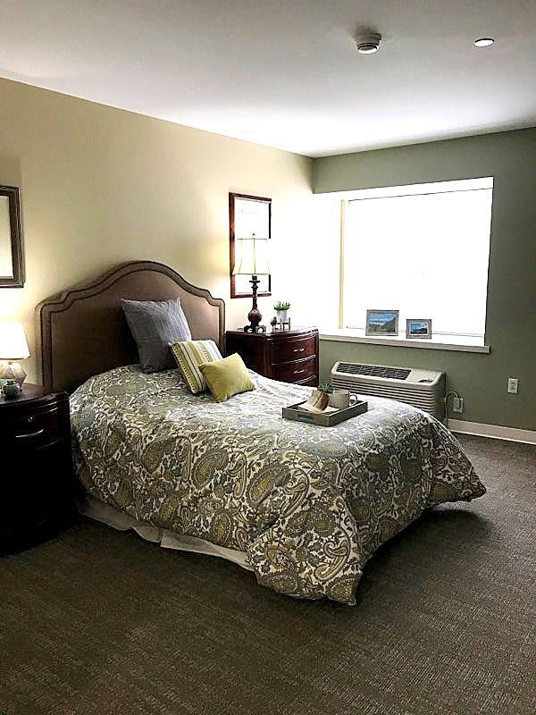 A cozy bedroom with a neatly made bed, decorative pillows, and warm lighting.