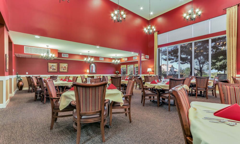 An elegantly decorated restaurant dining area with red walls, chandeliers, and neatly arranged tables and chairs.
