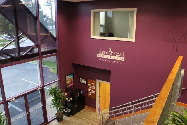 A view of a building's interior lobby area with a staircase, window, and signage on the wall.