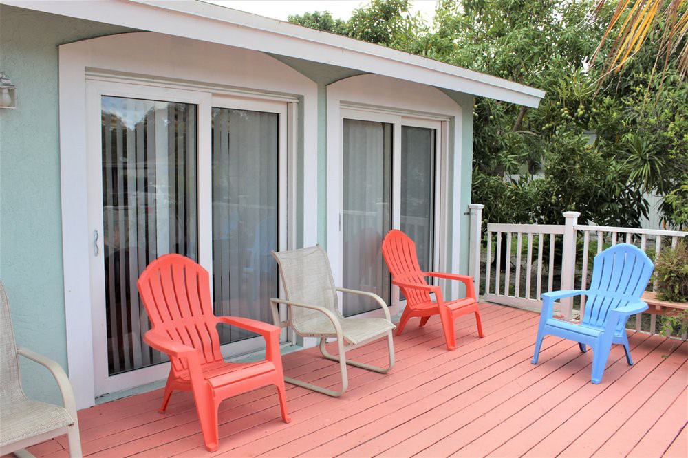 A cozy outdoor patio with colorful chairs and sliding glass doors.