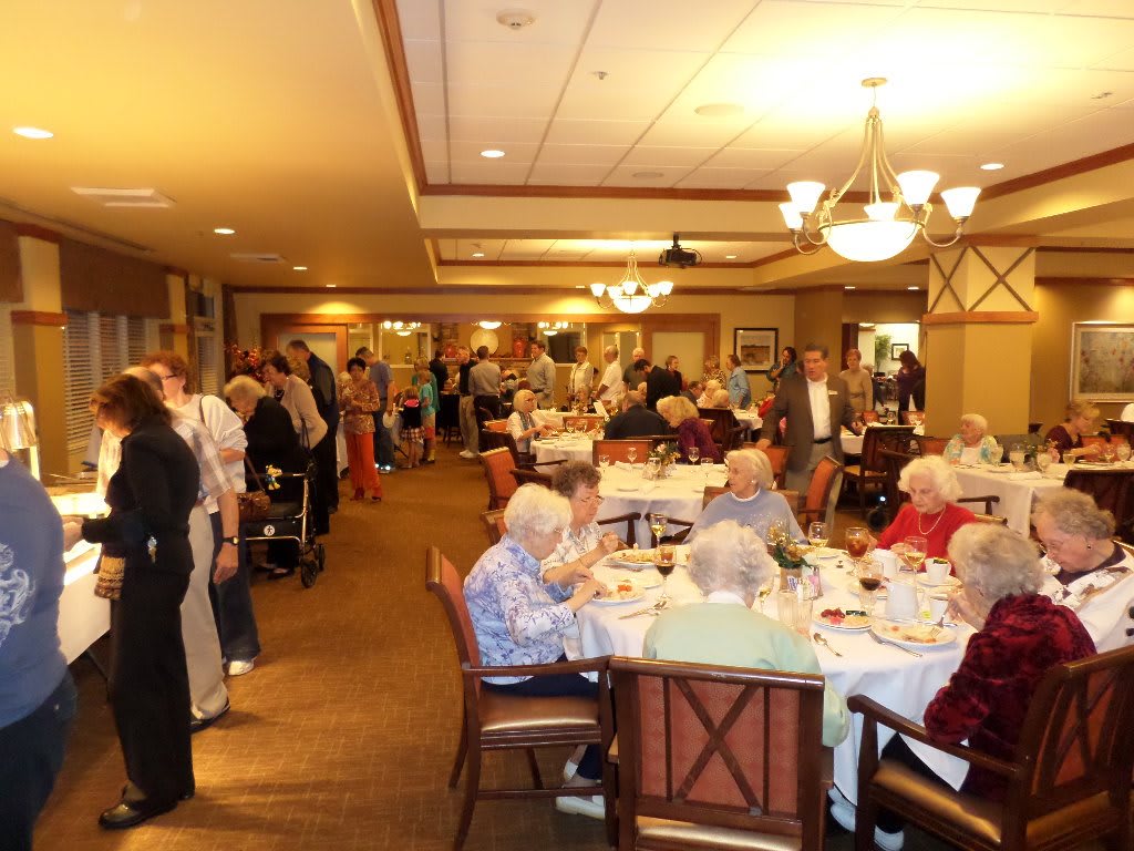 A group of elderly people enjoying a meal together in a dining hall setting.