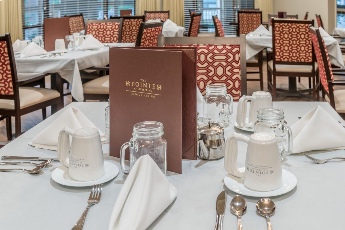 An elegant dining room setup with neatly arranged place settings and a menu on display.