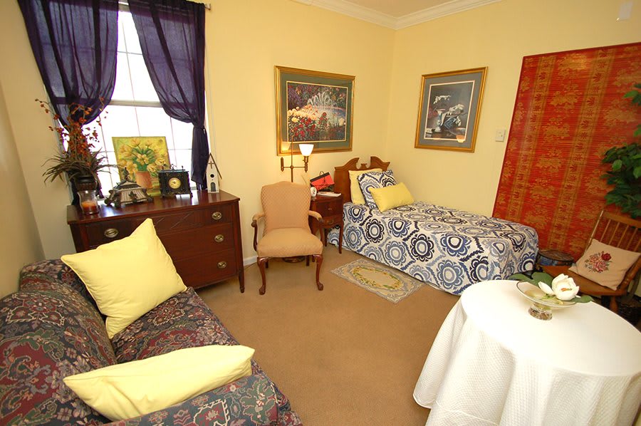 A cozy bedroom with a single bed, decorated with framed art and soft lighting.
