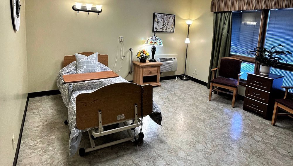 A clean and organized hospital patient room with a single bed and medical equipment.