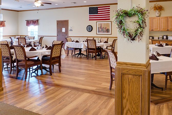 A cozy dining area with wooden flooring, adorned with an American flag and a decorative wreath on the wall.