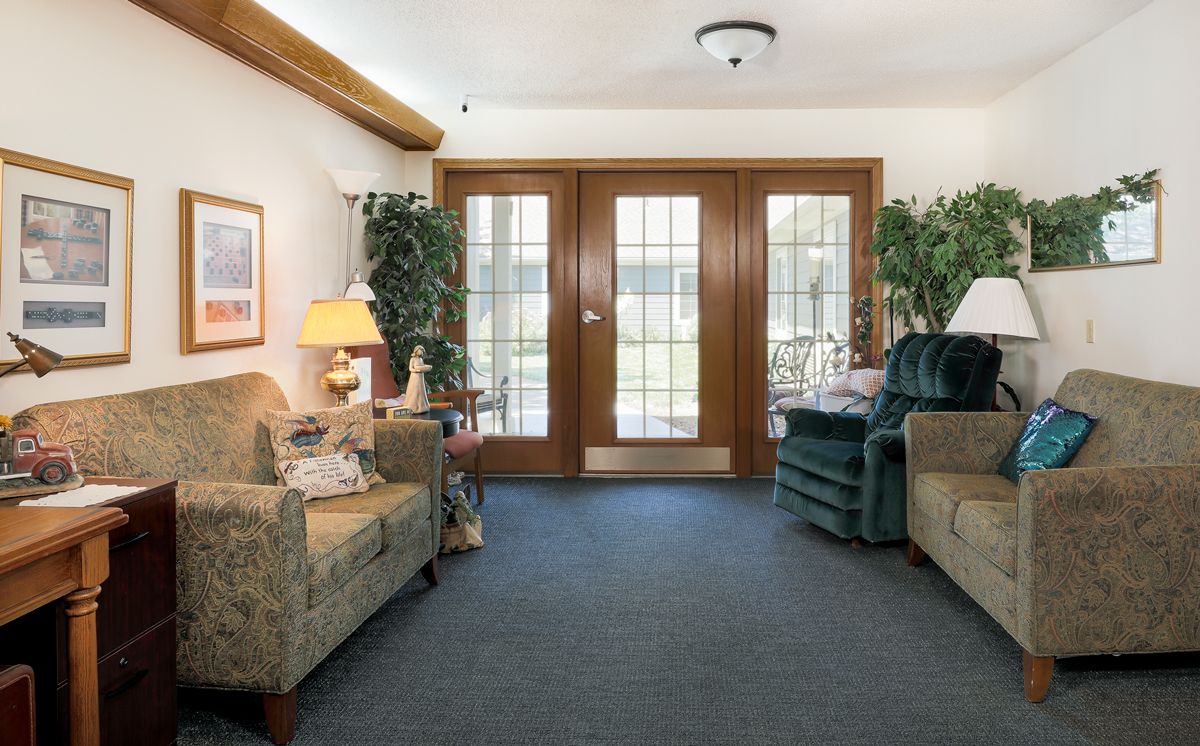 A cozy living room with sofas and wooden doors letting in natural light.