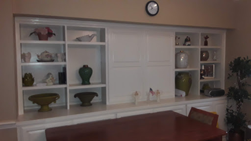 A contemporary interior featuring decorative shelves with various vases and a wall clock.