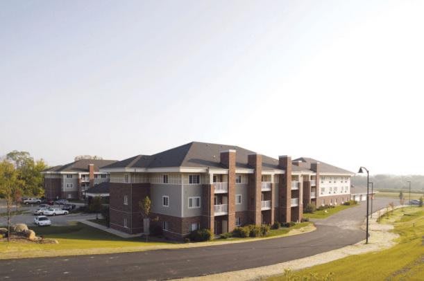 A modern suburban apartment building with a brick and siding exterior.