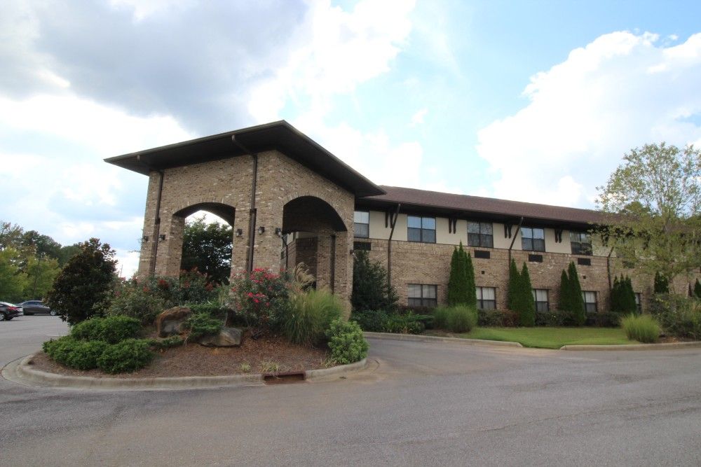 A two-story brick building with landscaped surroundings under a partly cloudy sky.