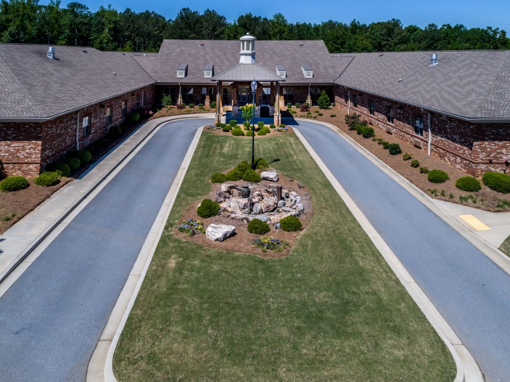 Aerial view of a symmetrical building with a landscaped driveway.