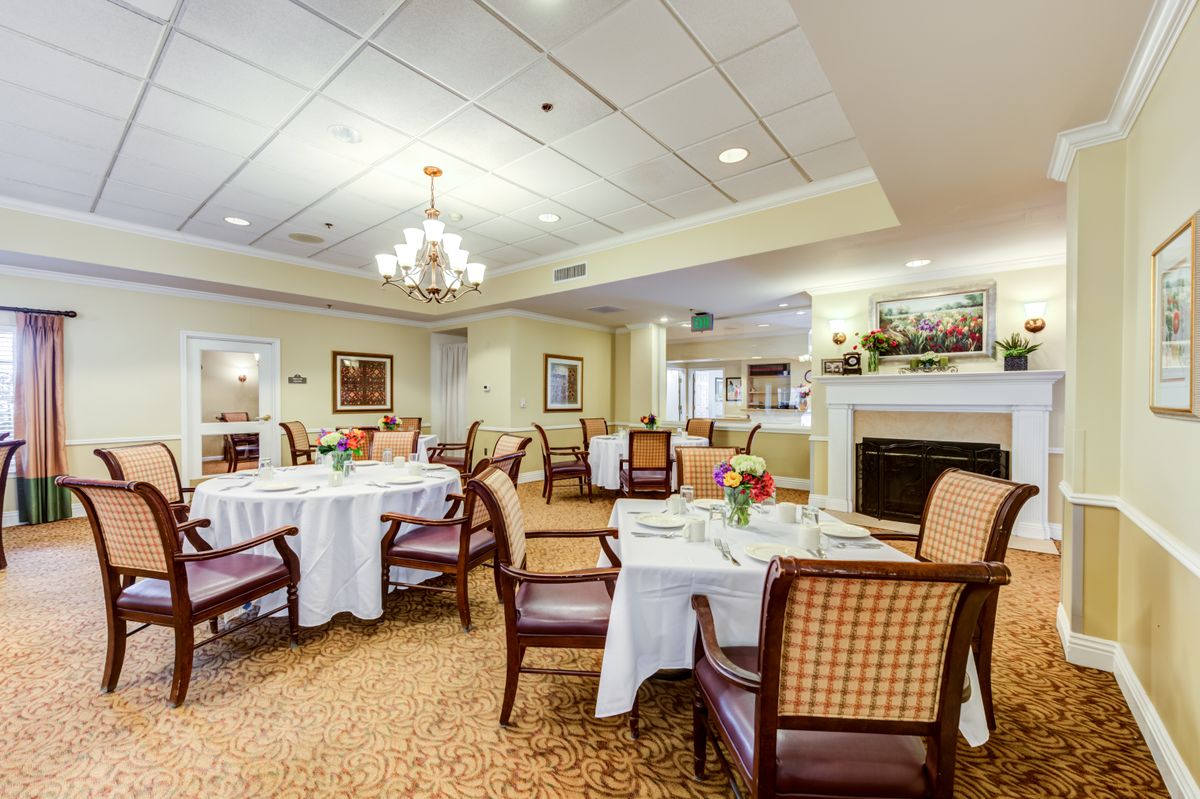 An elegant dining room with neatly arranged tables and chairs, featuring a chandelier and tasteful decor.