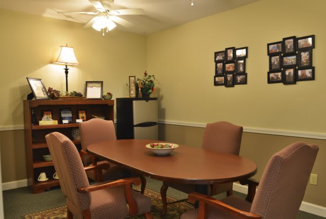 A cozy conference room with a wooden table, several chairs, and framed photos on the wall.