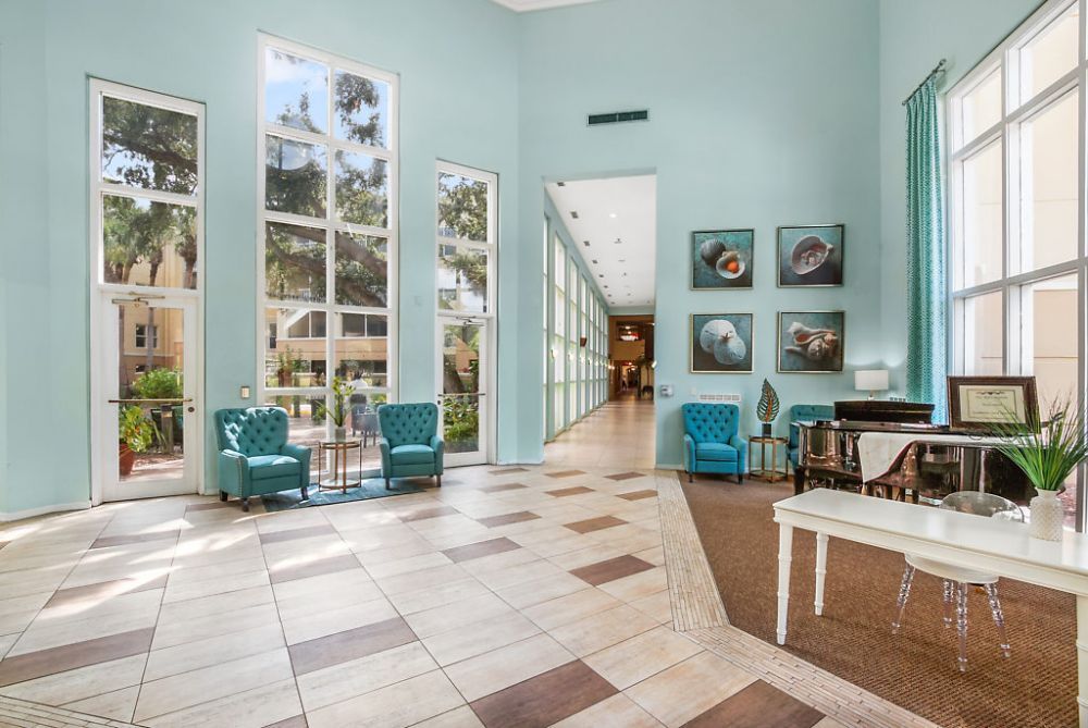 A bright and spacious lobby with large windows, modern furniture, and decorative art on the walls.