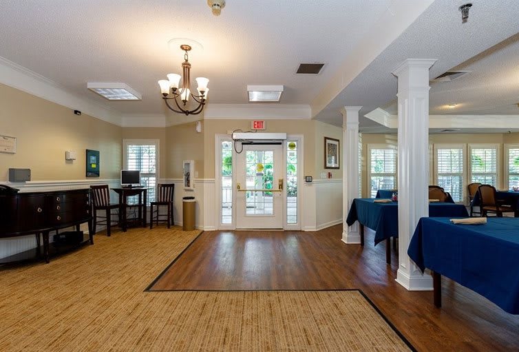 A well-lit lobby area with a central entrance, featuring wooden flooring and elegant furnishings.