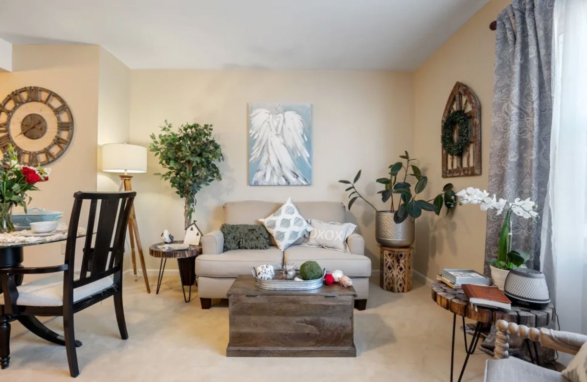 A cozy living room with a sofa, coffee table, and various plants and decor.
