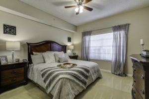 A cozy bedroom with a large bed, lamp, and window with curtains.