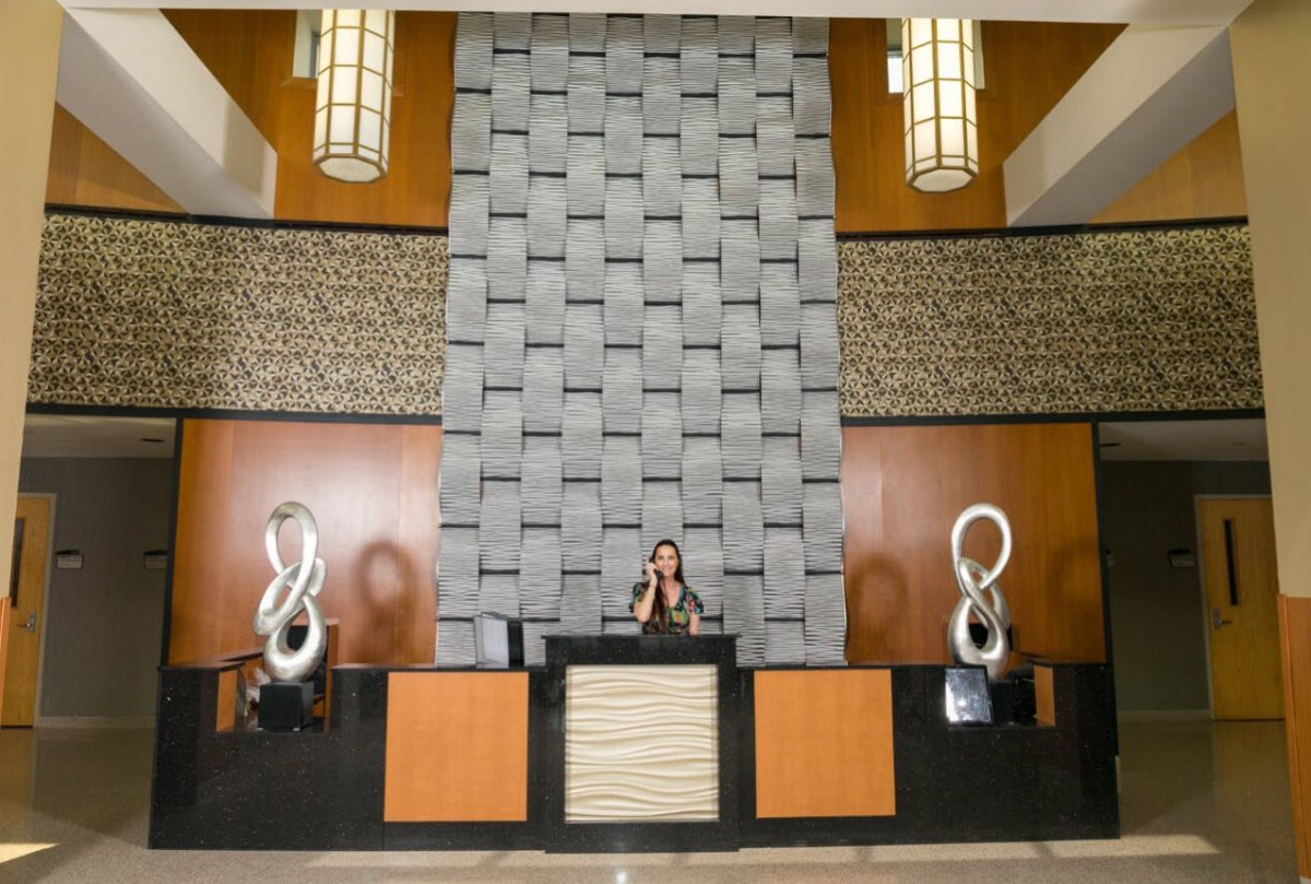 A modern hotel lobby with a reception desk and decorative sculptures.