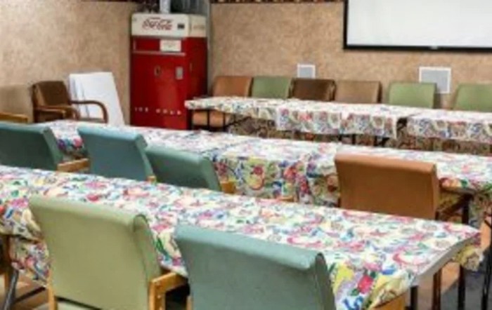 A cozy indoor cafe setting with colorful tablecloths on tables and a retro refrigerator in the background.