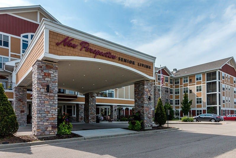 Entrance of a senior living facility with stone pillars and landscaped surroundings.