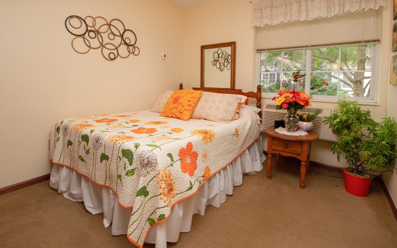 A cozy bedroom with a floral-themed bedspread and decorative elements.