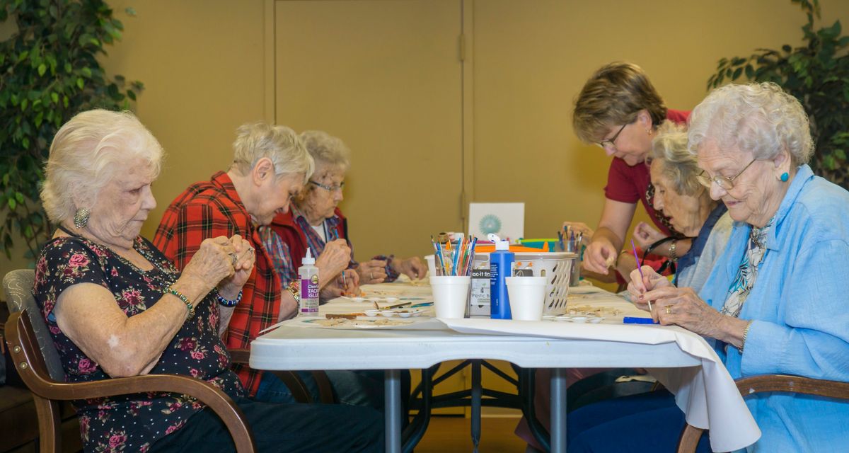 A group of people participating in an arts and crafts activity at a table indoors.