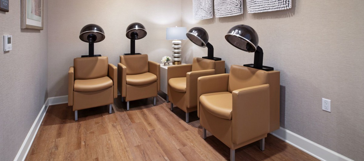 A modern salon interior with comfortable chairs and hair dryers.