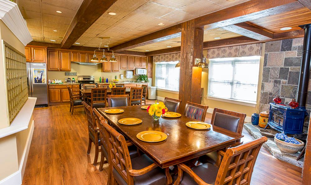 A spacious dining area with a large wooden table and chairs, adjacent to a modern kitchen.