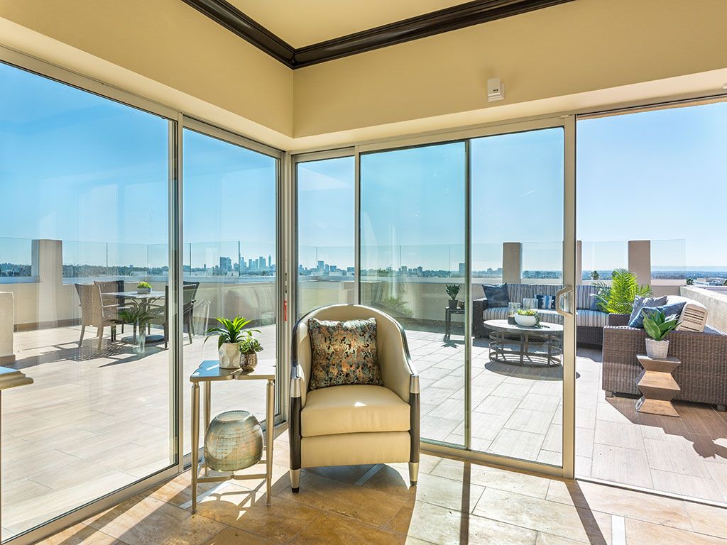 A modern living room with floor-to-ceiling glass doors opening to a spacious balcony overlooking the city.
