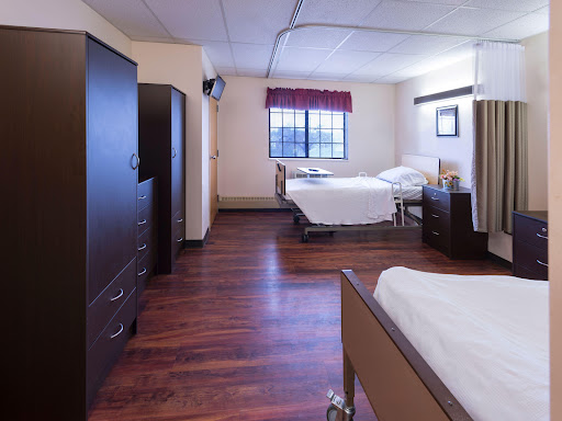 A well-lit hospital patient room featuring two beds and essential furniture.