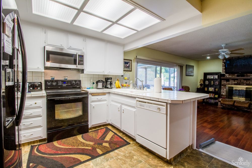 A modern kitchen with white cabinets, featuring an oven, microwave, and a countertop island.