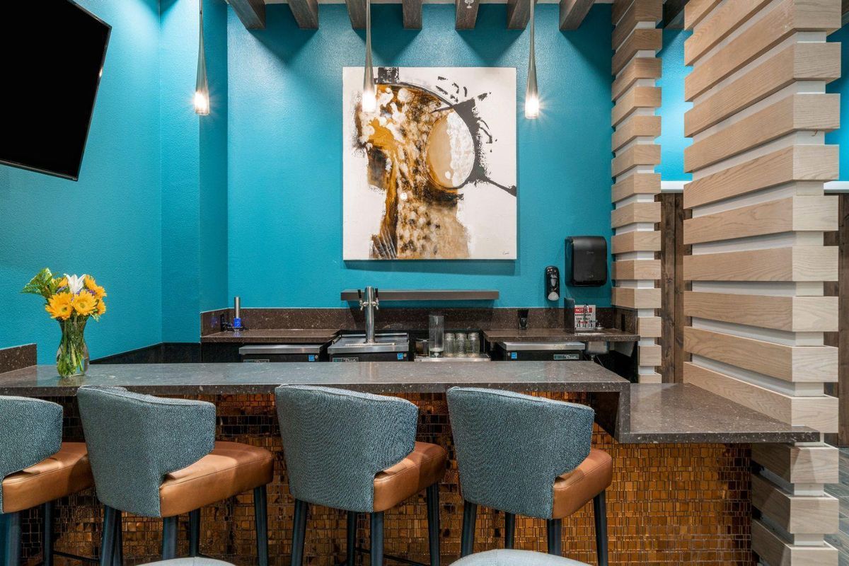 A modern bar interior with blue walls and stylish seating.
