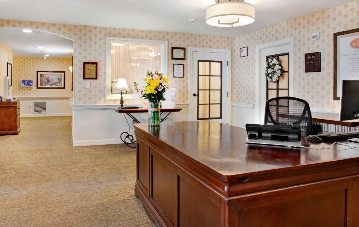A well-decorated reception area with a wooden desk and floral arrangement.